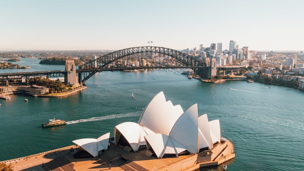 Sydney Opera House with the Harbour Bridge and city skyline visible across the harbor in the background.